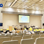 都民ホールの会場内。スクリーンにイベントロゴが投影されている。