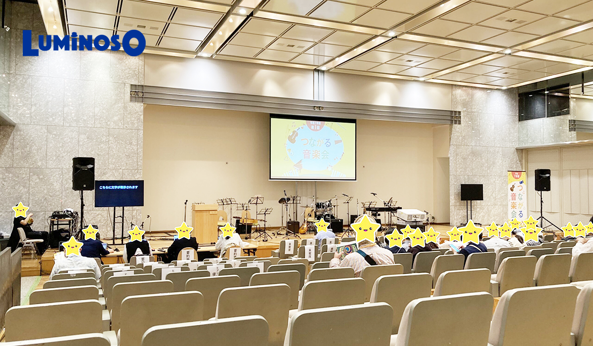 都民ホールの会場内。スクリーンにイベントロゴが投影されている。